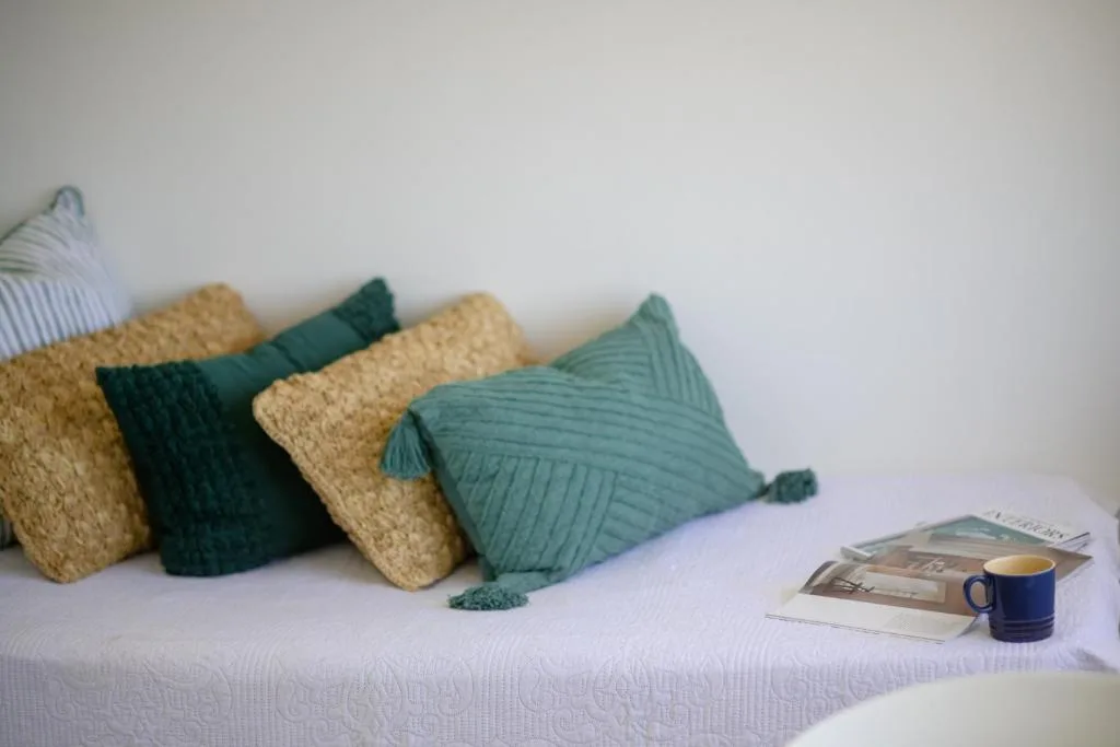 Decorative pillows and coffee mug arranged on a white bed