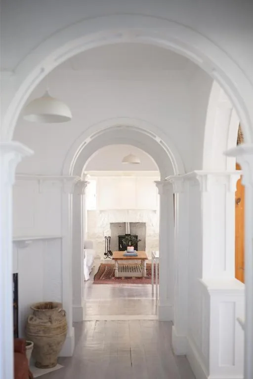 White arched hallway with terracotta pot, leading to bright interior spaces