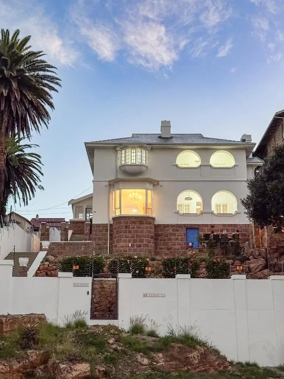 Contemporary villa with white walls and brick features at dusk, palm tree visible