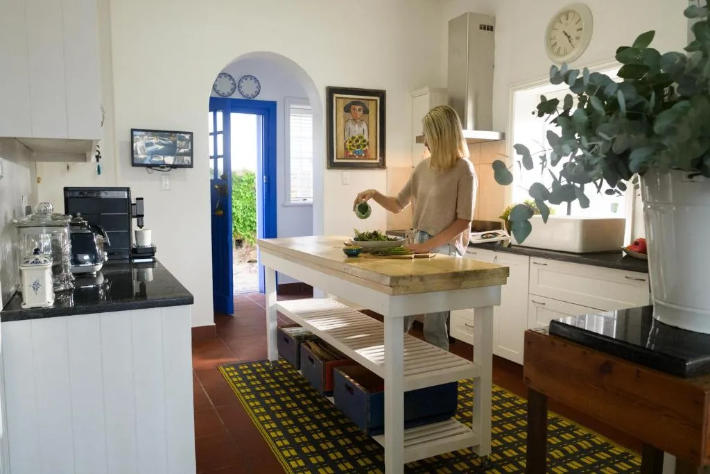 Woman preparing fresh vegetables at wooden island counter in bright kitchen