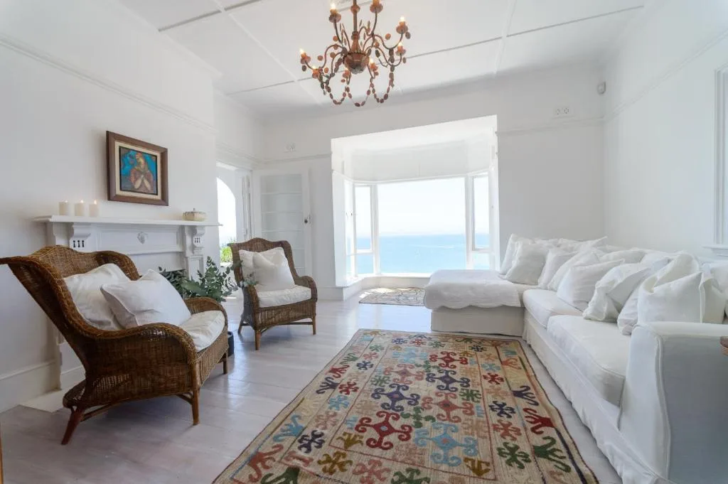 Bright white lounge with ocean view doors, rattan chairs, and coastal decor