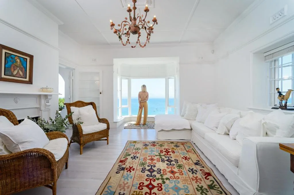 Bright beachfront lounge with white sofas, wicker chairs, and ocean view