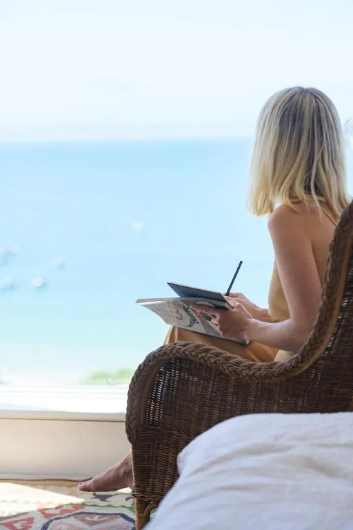 Woman relaxing on wicker chair overlooking calm blue ocean horizon
