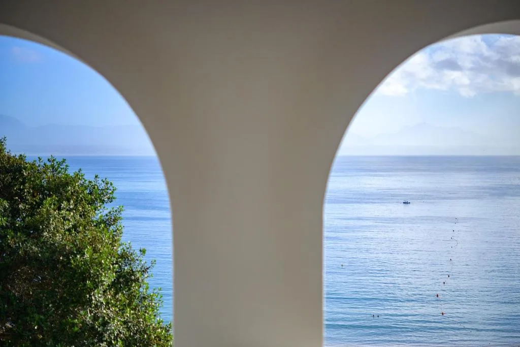 Stunning ocean view framed through white arches with coastal vegetation
