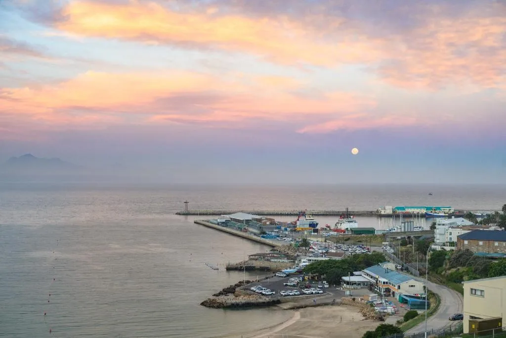 Mossel Bay harbor and beach at sunset with moon rising over water