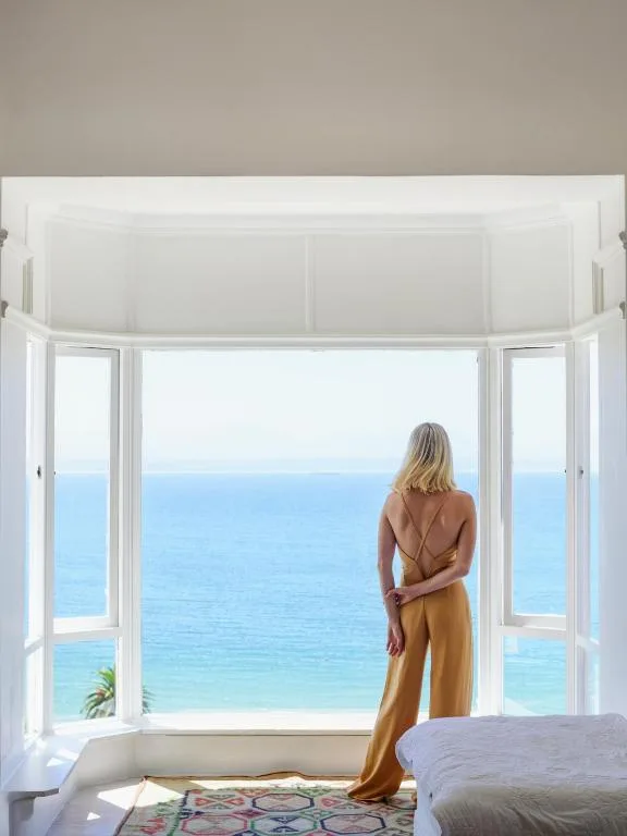 Woman gazing at expansive ocean and beach views from bedroom windows