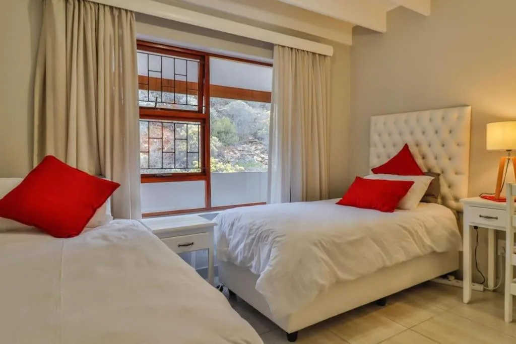 Bright bedroom with twin beds, red accents, mountain views through large windows