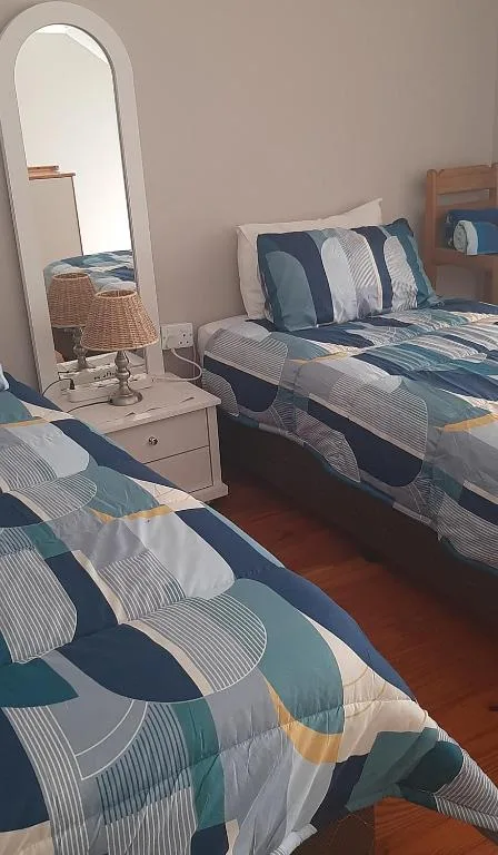 Bright bedroom with two beds, geometric patterned bedding, and vanity mirror