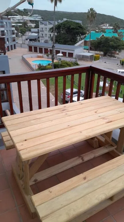Wooden table on balcony overlooking pool and coastal hillside