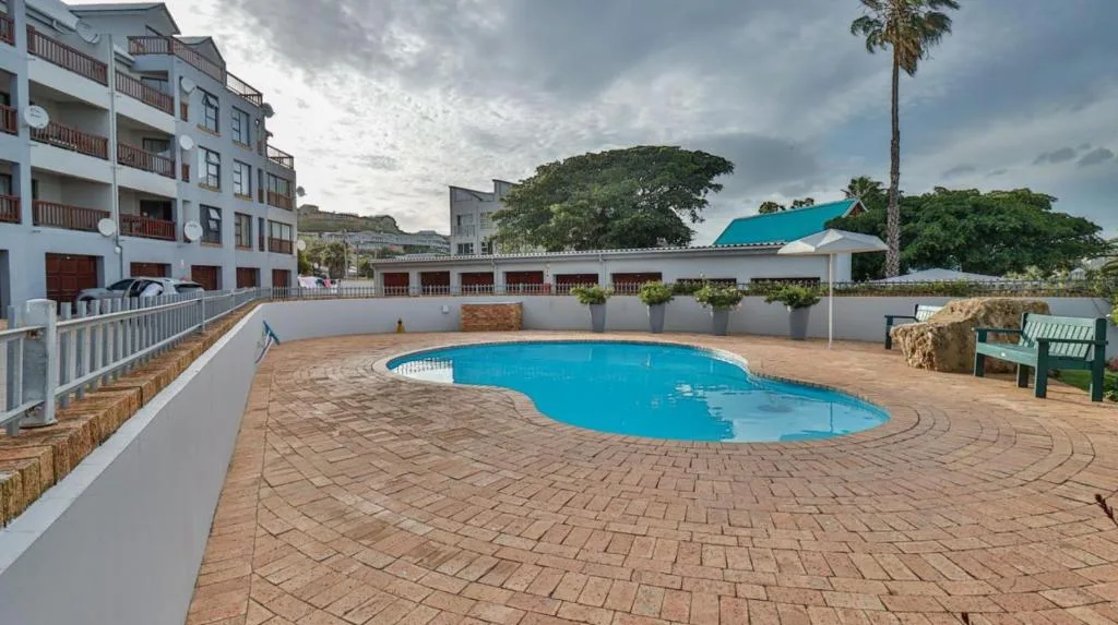 Kidney-shaped swimming pool in brick courtyard surrounded by apartment buildings