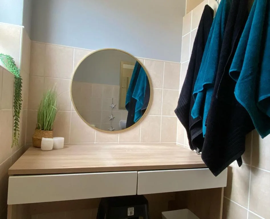 Modern bathroom vanity with round mirror, wooden countertop, and fresh plants