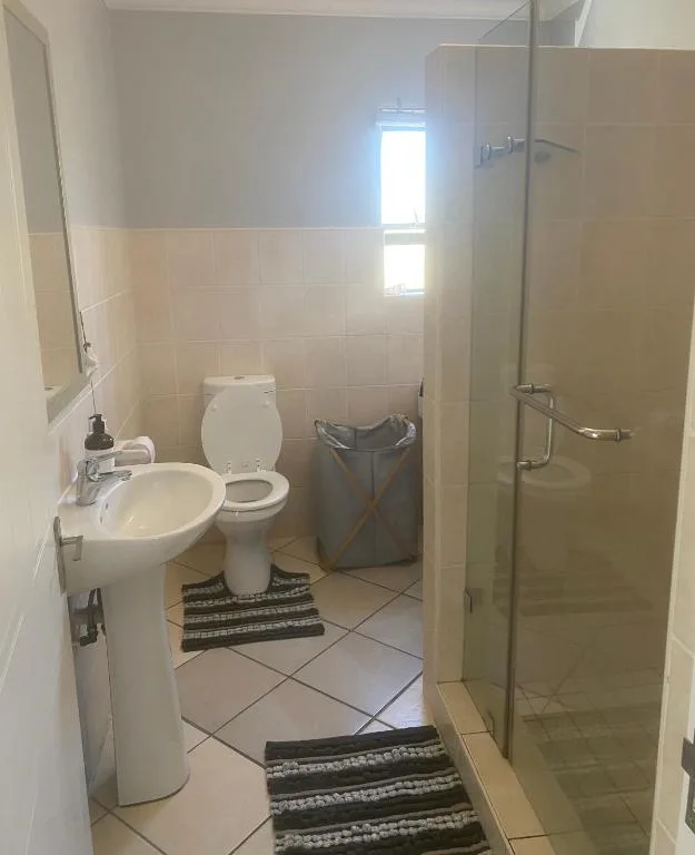 Clean bathroom with toilet, pedestal sink, and walk-in shower enclosure