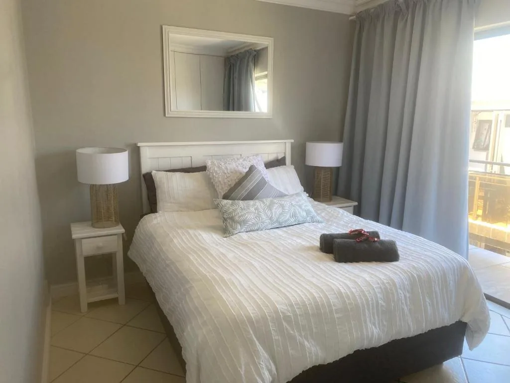 Bright bedroom with queen bed, white headboard, and bedside lamps
