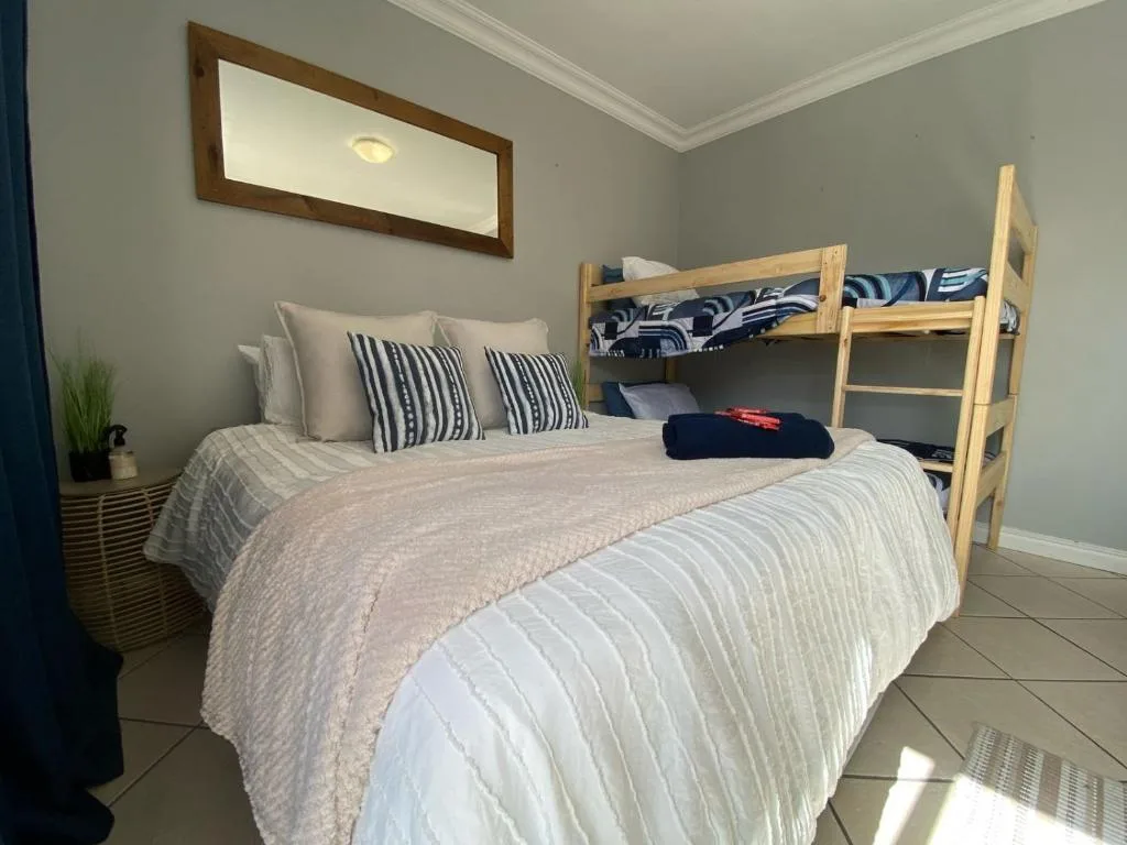 Bright bedroom with double bed, striped pillows, and wooden bunk bed