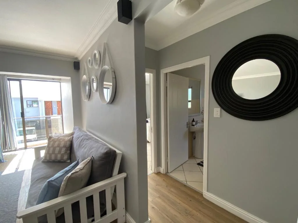 Modern bedroom with white cot, decorative wall mirrors, and sliding door to balcony
