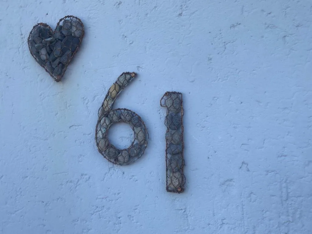 Heart-shaped decoration and house number sixty-one on pale blue wall