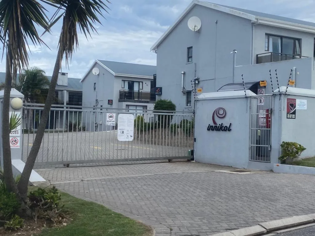 Modern white apartment building with secure gated entrance and palm tree landscaping