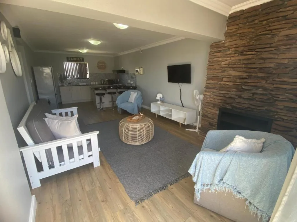 Open-plan lounge with sofas, TV, fireplace, and kitchen area visible