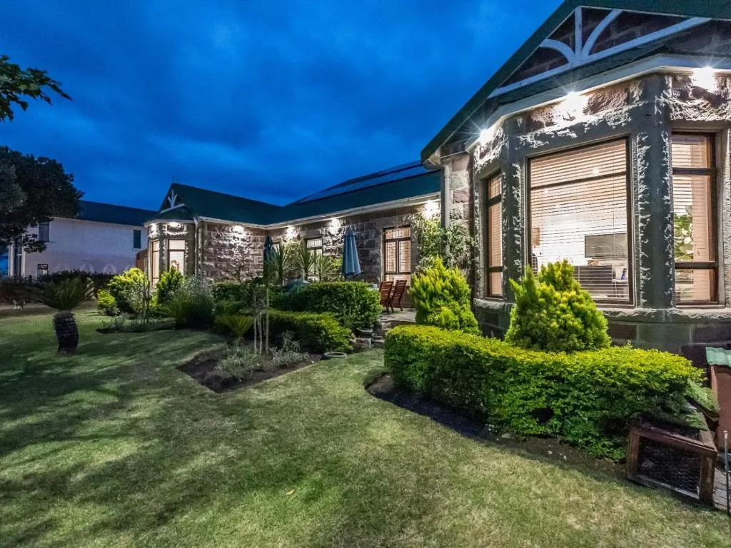 Charming stone cottage exterior illuminated at dusk with manicured gardens