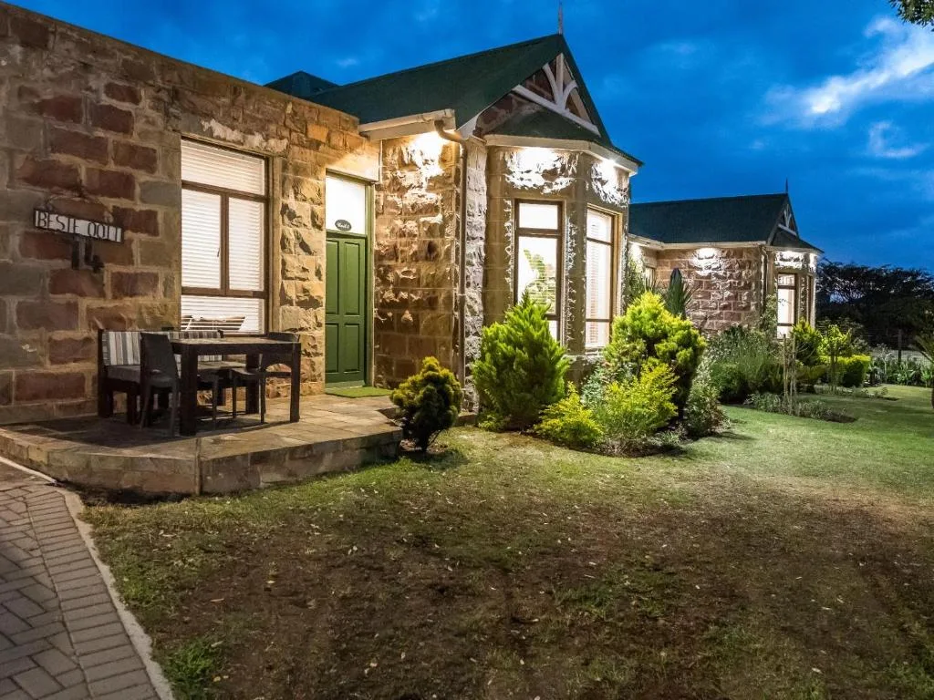 Stone cottage exterior with green door and manicured garden at dusk