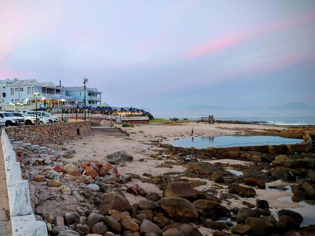 Rocky beach at sunset with seaside accommodation building and coastal landscape