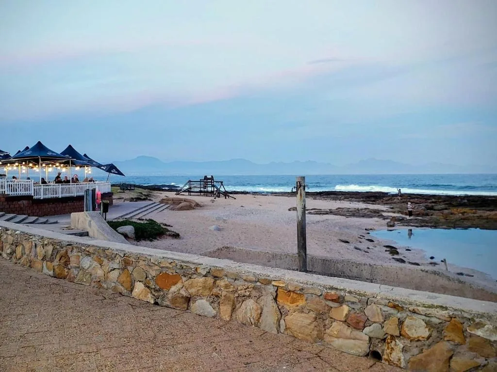 Scenic coastal sunset view with ocean, beach, and mountains in distance