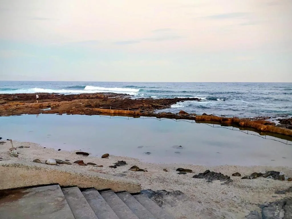 Scenic ocean view with rocky coastline and tidal pool at sunset