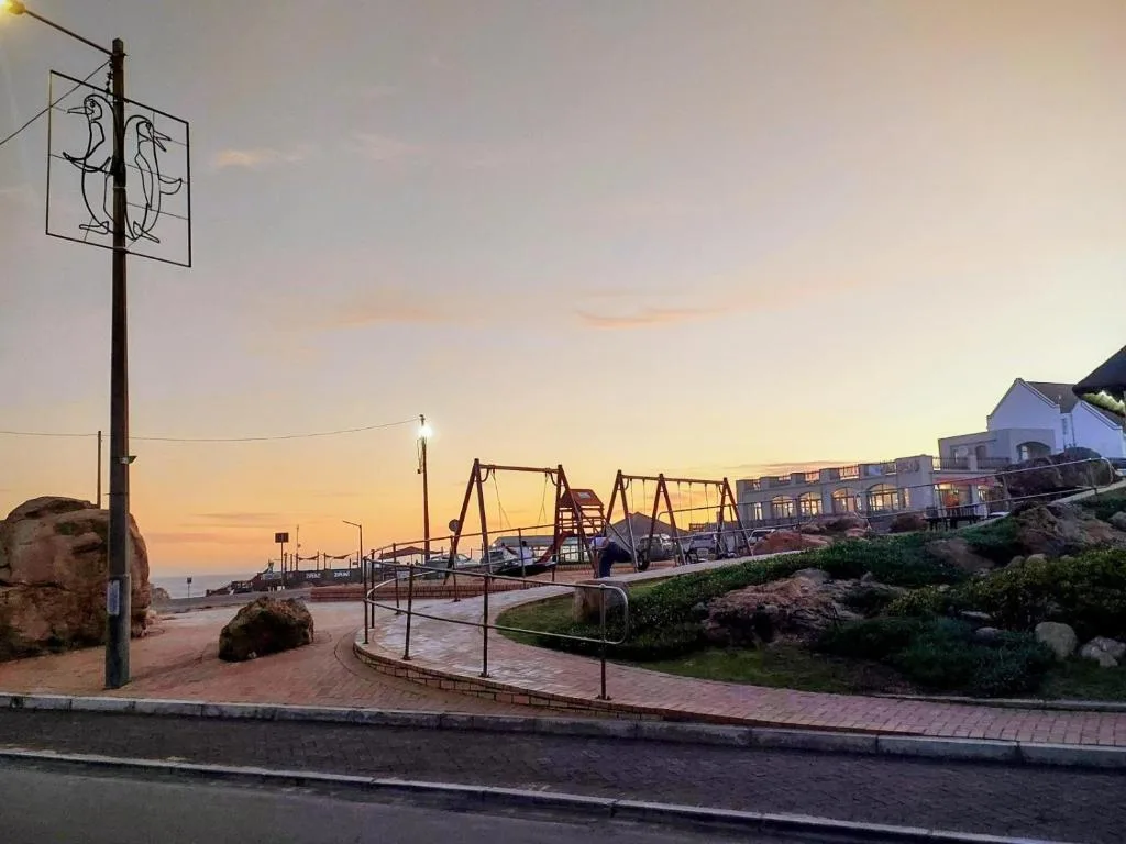 Sunset coastal village scene with playpark and residential buildings nearby