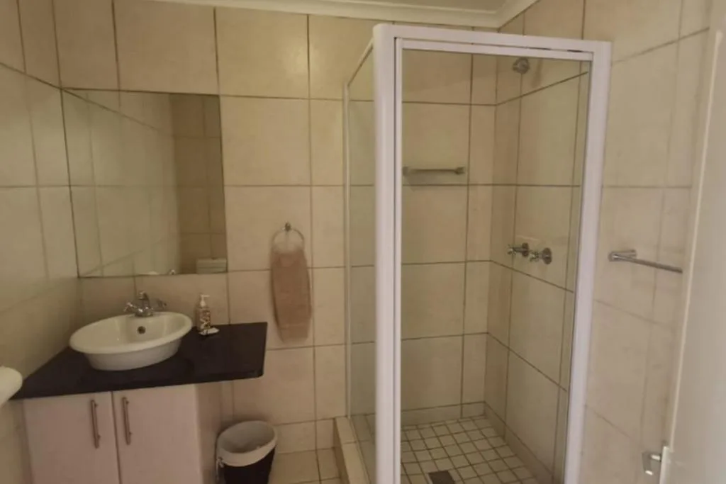 Modern bathroom with round sink, white vanity, glass shower enclosure