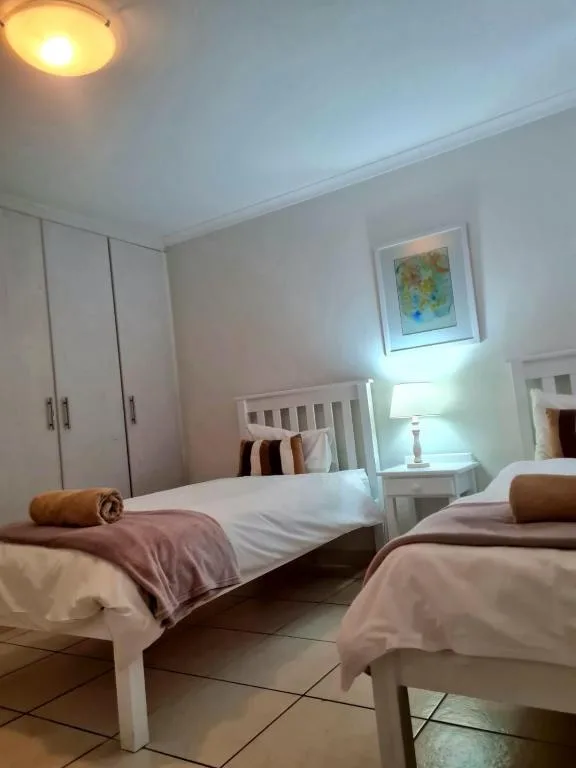Twin bedroom with white beds, pink throws, and built-in wardrobe