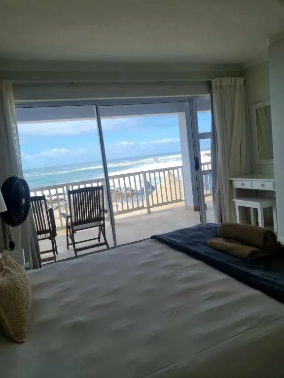 Spacious bedroom with ocean view through glass doors opening to balcony