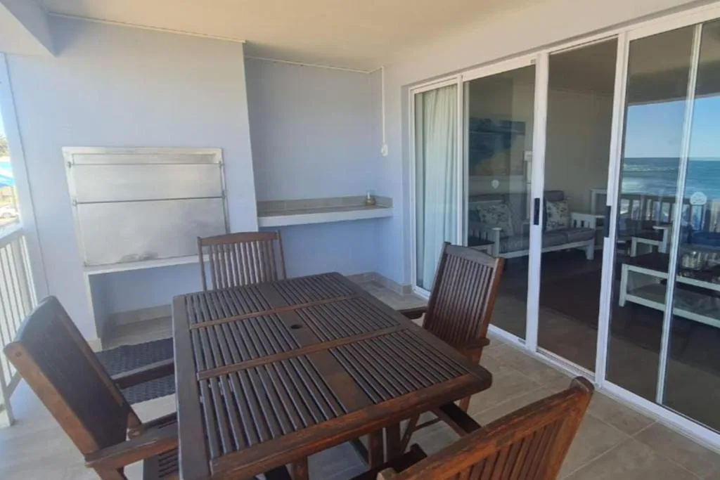 Wooden dining table and chairs on oceanview balcony with sliding glass doors