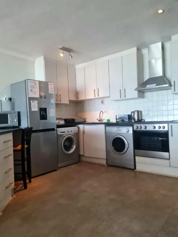 Modern kitchen with white cabinetry, stainless steel appliances, and washing machines