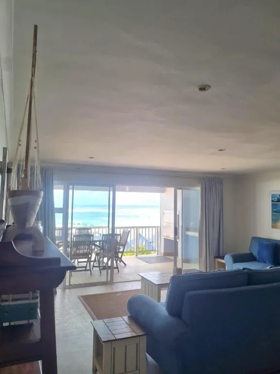 Spacious lounge with blue sofa overlooking ocean through sliding glass doors