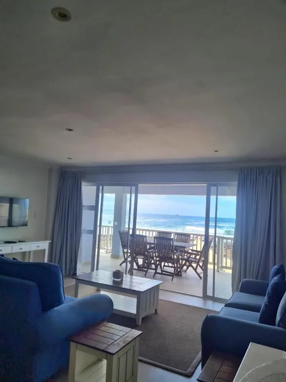 Spacious lounge with blue armchairs overlooking ocean view through glass doors