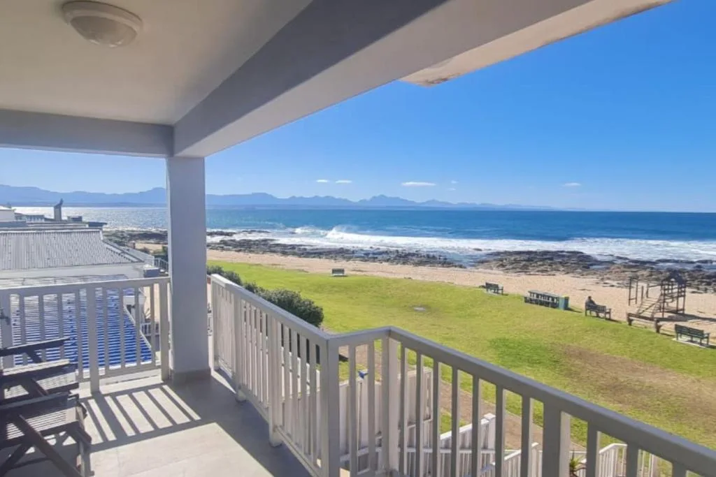 Ocean, beach, and mountain scenery from covered deck with railings