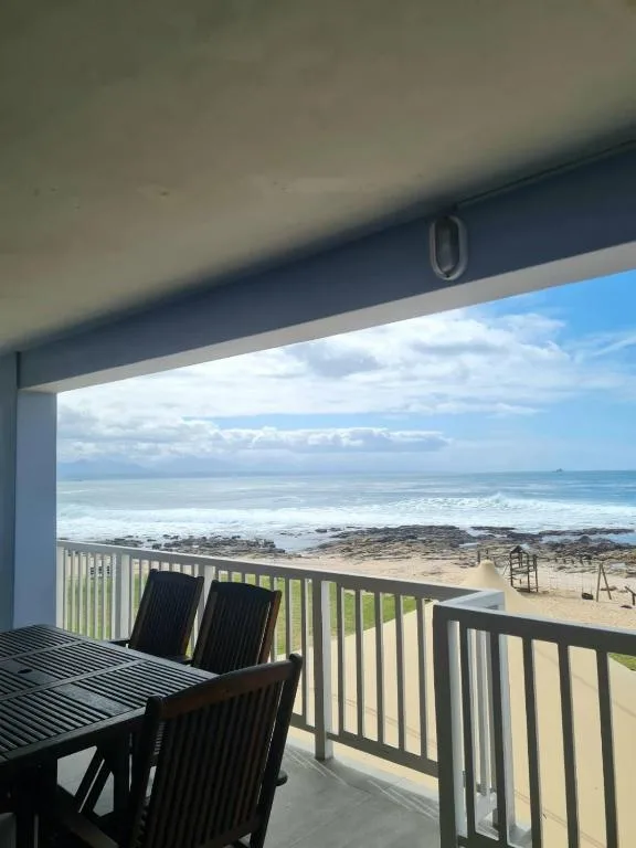 Ocean and beach vista from covered deck with dining furniture