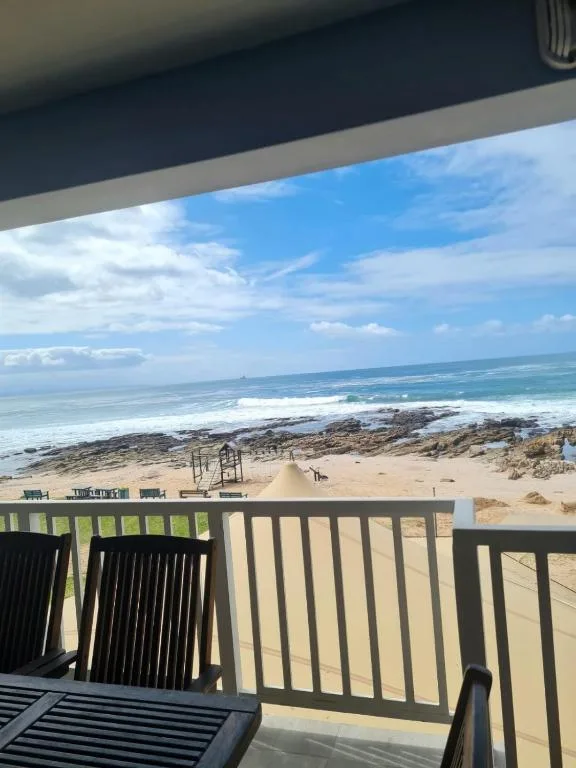 Ocean and beach view from covered deck with railings and seating