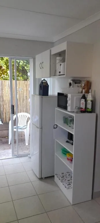 Modern kitchen with white refrigerator, open shelving, and outdoor access door
