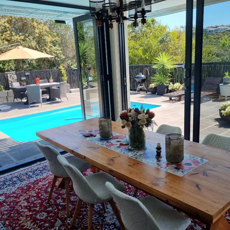 Covered deck with dining table overlooking swimming pool and garden area