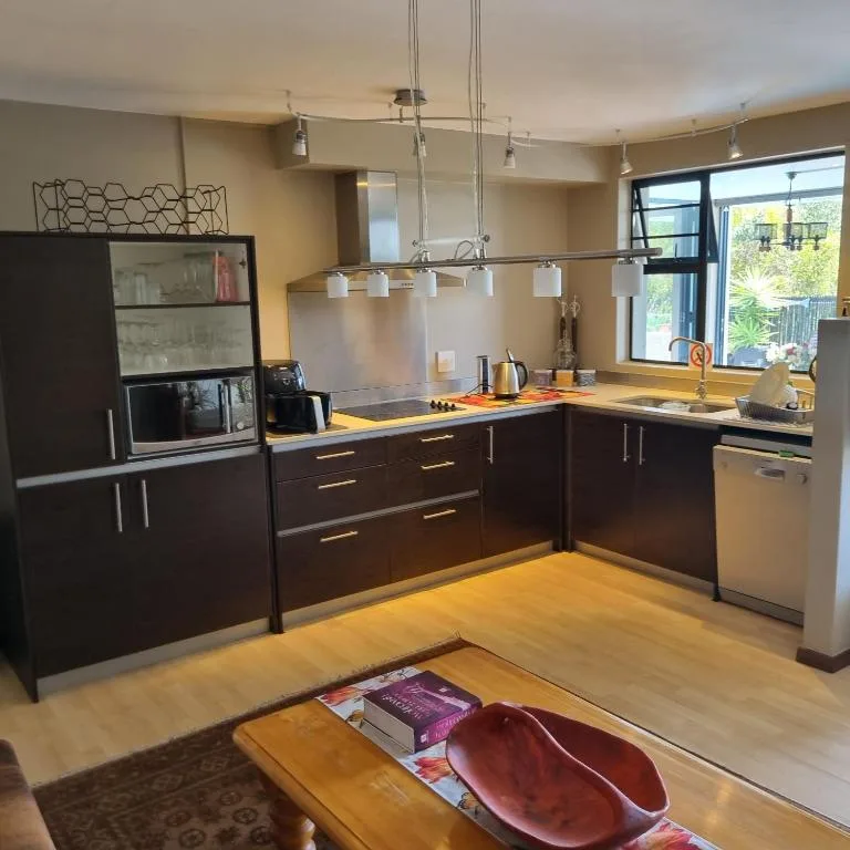 Modern kitchen with dark cabinetry, stainless steel appliances, and pendant lighting