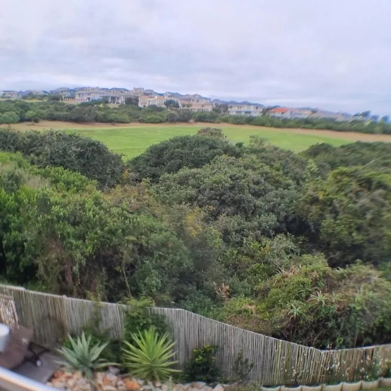 Scenic vista of green valleys, mountains and distant properties under cloudy sky