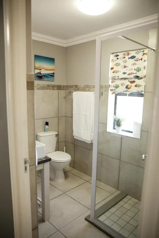 Clean bathroom with toilet, shower enclosure, and coastal-themed window treatment