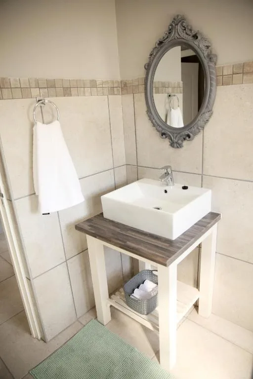 Modern bathroom vanity with white vessel sink and decorative mirror