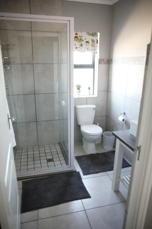 Modern bathroom with enclosed shower, toilet, and window with natural light