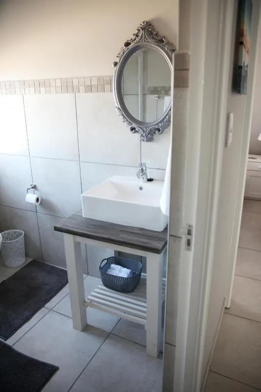 Modern bathroom vanity with white vessel sink and ornate mirror