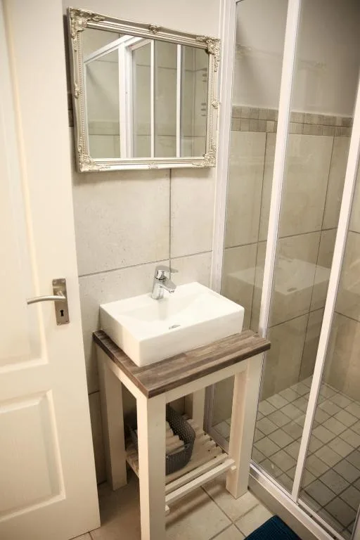 Bathroom vanity with white vessel sink and framed mirror above