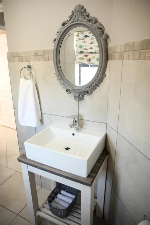 Bathroom vanity with white vessel sink and ornate oval mirror