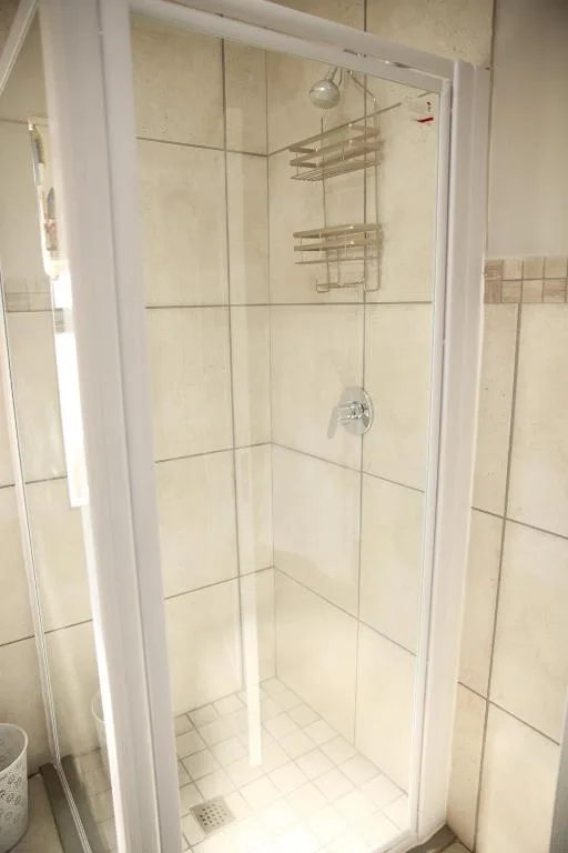 Clean modern shower enclosure with cream tiles and chrome fixtures
