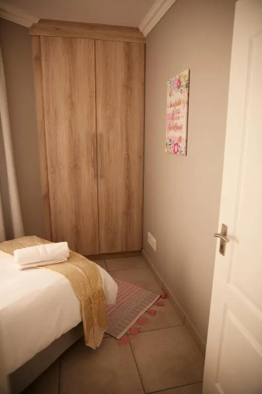 Compact bedroom with single bed, wooden wardrobe, and neutral decor
